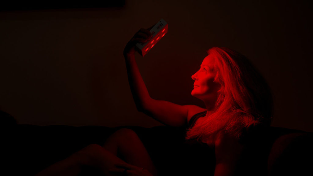 Older woman holding a red light therapy device in front of her